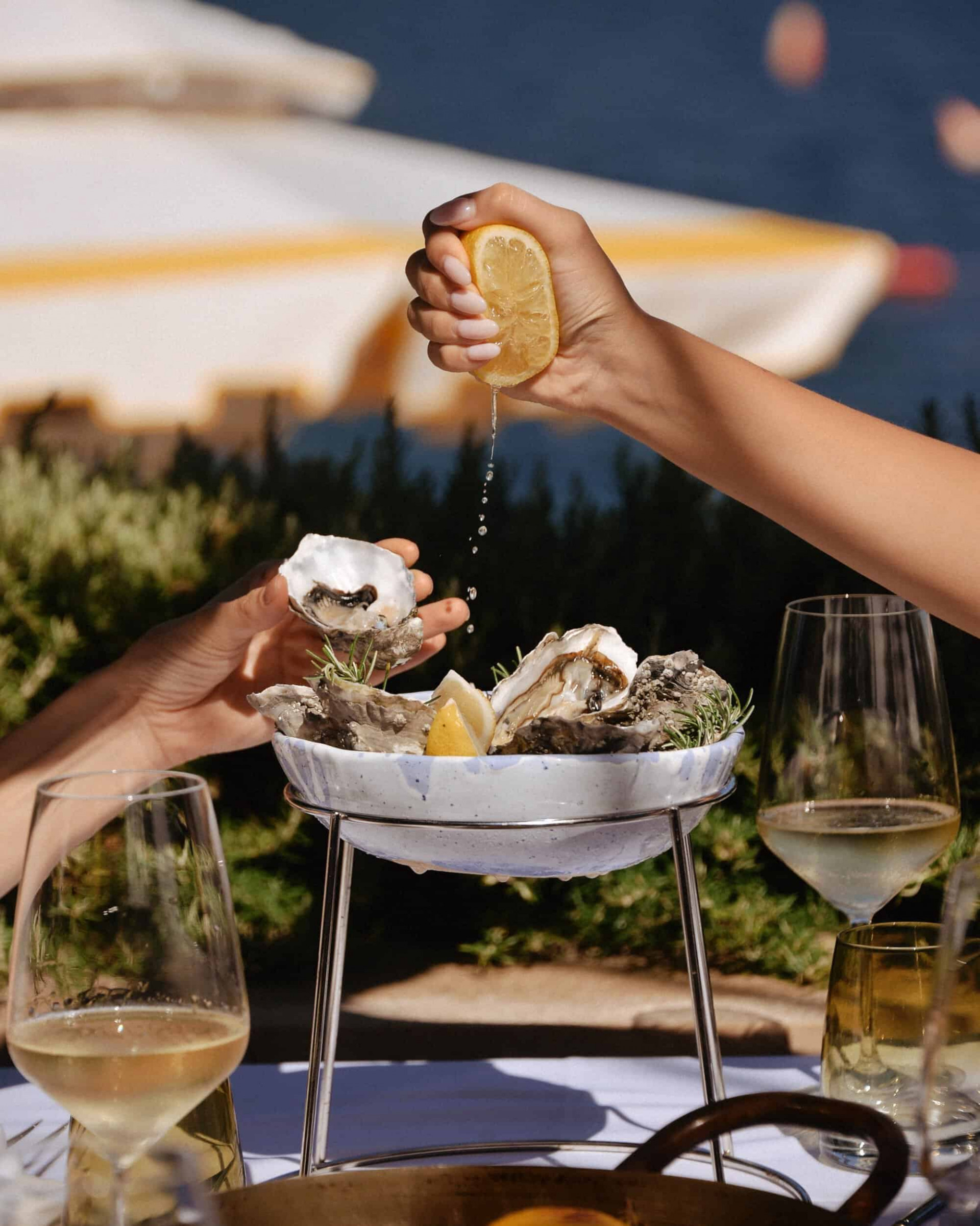 Lemon being squeezed over oysters on a table by the sea in Montenegro
